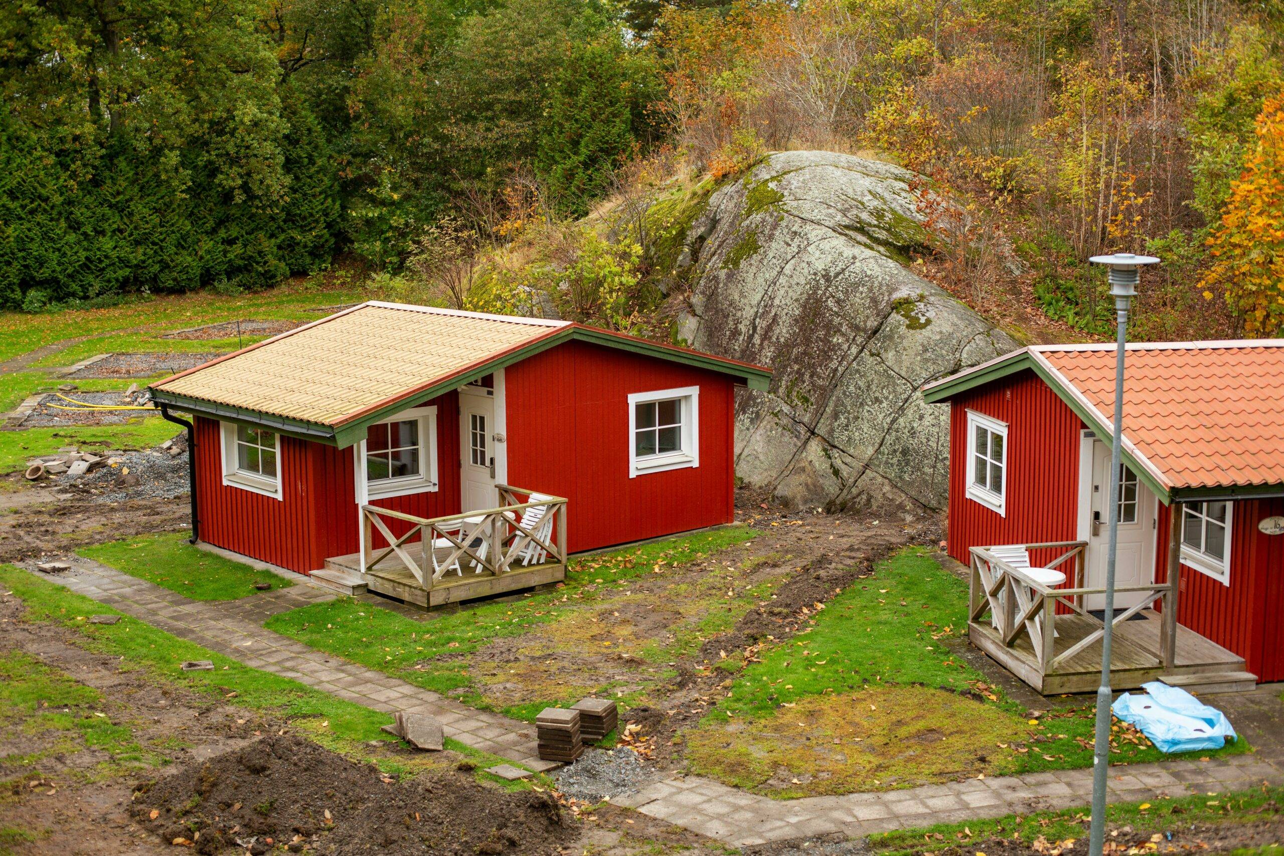 Cozy red cottage in Grönskara, Småland, serviced by Småland Holiday Home Care, nestled in a lush autumn landscape, showcasing local Swedish charm and care excellence.